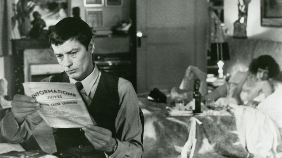 Młody mężczyzna siedzi przy stole i czyta gazetę