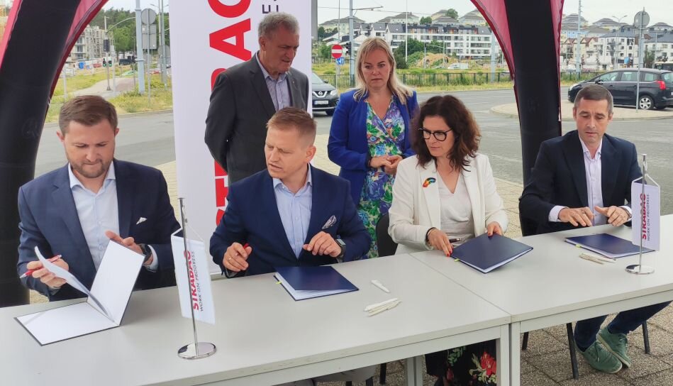 Podpisanie umowy przez cztery osoby pod namiotem eventowym