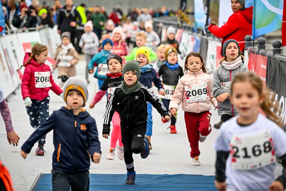 Dzieci biegnące w grupie, ubrane w czapki i cieplejsze bluzy lub w koszulkach z numerami