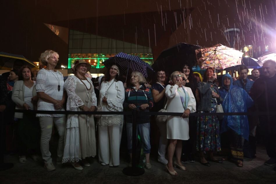 deszcz nocą, pod parasolami kobiety z widowni