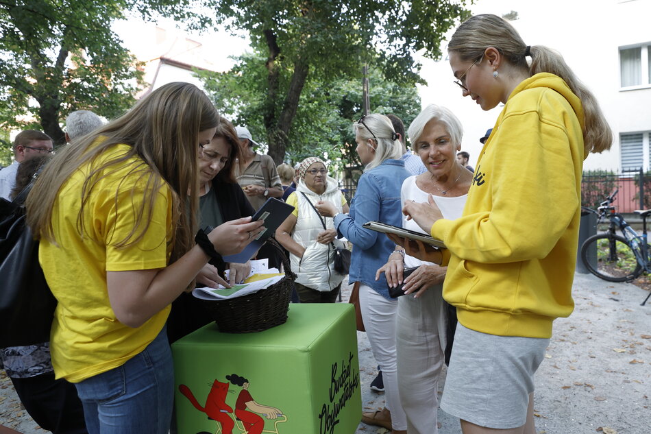 konsultanci Budżetu Obywatelskiego w żółtych koszulkach pomagają głosować mieszkańcom