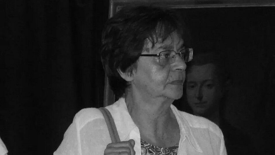Czarno białe zdjęcie: kobieta w okularach w średnim wieku z przewieszoną przez ramię torebką