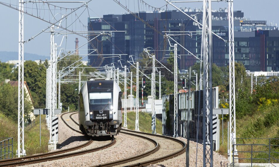 pociąg na szynach na tle nowoczesnych biurowców