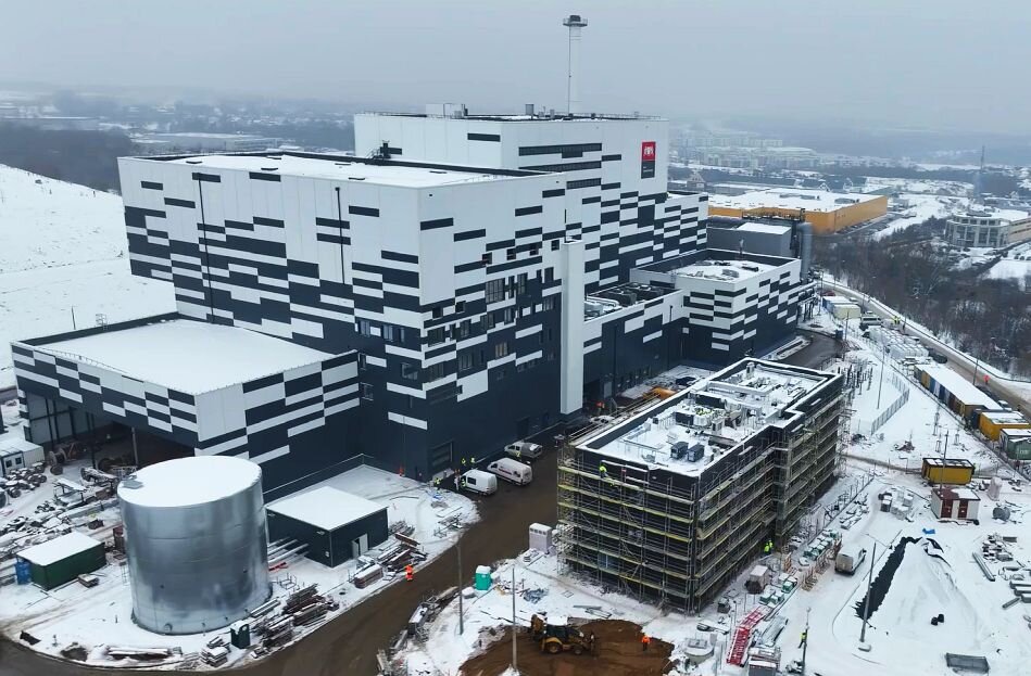 ogromny zakład z kominem na tle zimowych pół