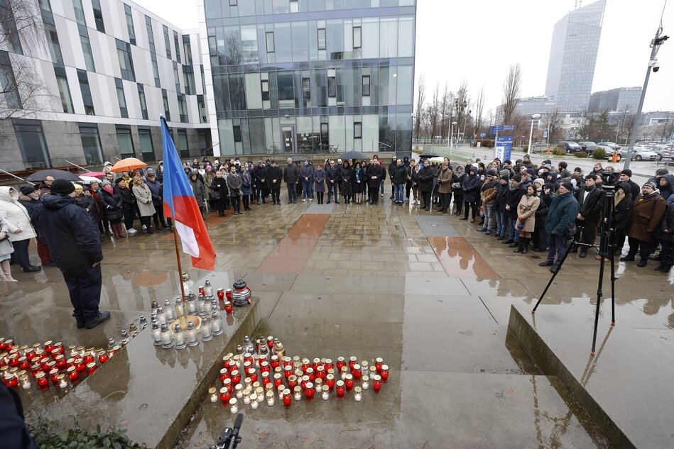 w deszczu na placu stoi kilkadziesiąt osób, przed nimi flaga polska i czeska, na ziemi znicze