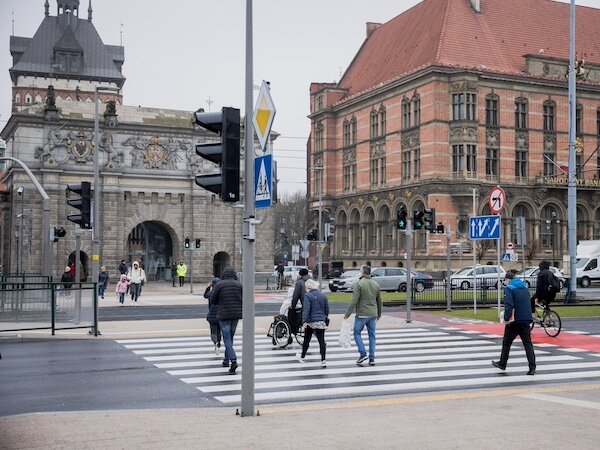 Przejście dla pieszych i ścieżka rowerowa wzdłuż przejścia. W tle Brama Wyżynna i budynek Narodowego Banku Polskiego.