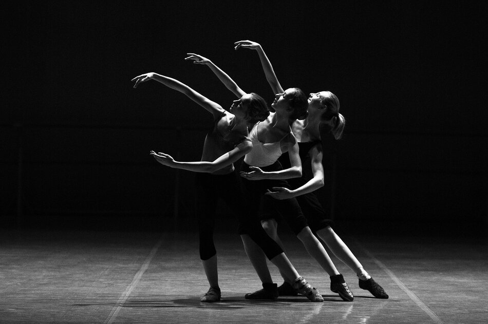 Trzy młode baletnice, stoją jedna za drugą na scenie, czarno-białe zdjęcie