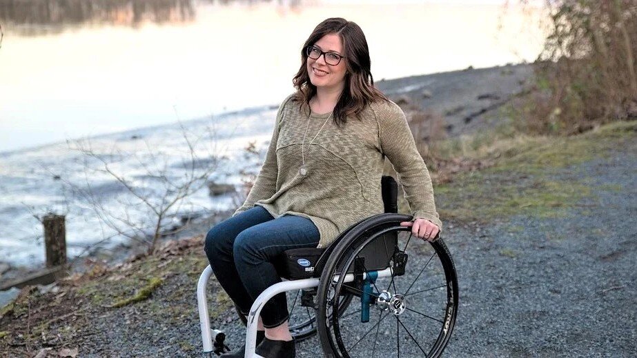 Kobieta siedzi na wózku inwalidzkim, uśmiecha się