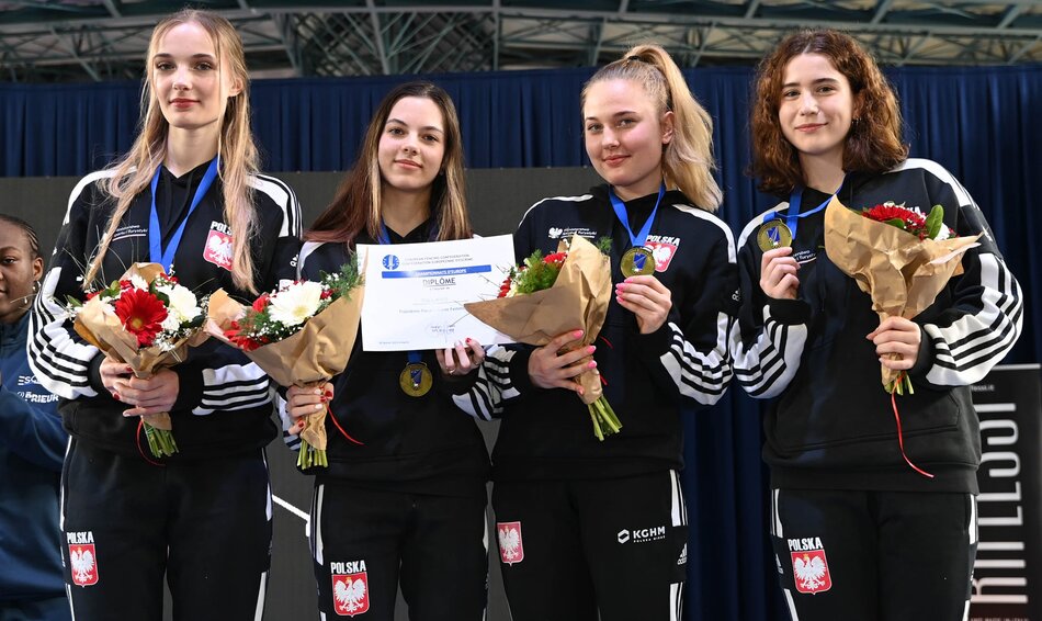 Cztery młode kobiety w dresach z kwiatami w dłoni i medalami na szyi