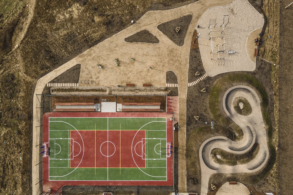 zdjęcie z drona, widać czerwono zielone boisko do gry, obok tor do jazdy na rowerach sportowych