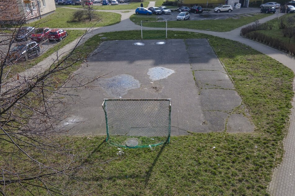 zdjęcie z drona, widać stare zniszczone asfaltowe boisko ze zniszczonymi metalowymi bramkami do gry w piłkę nożną