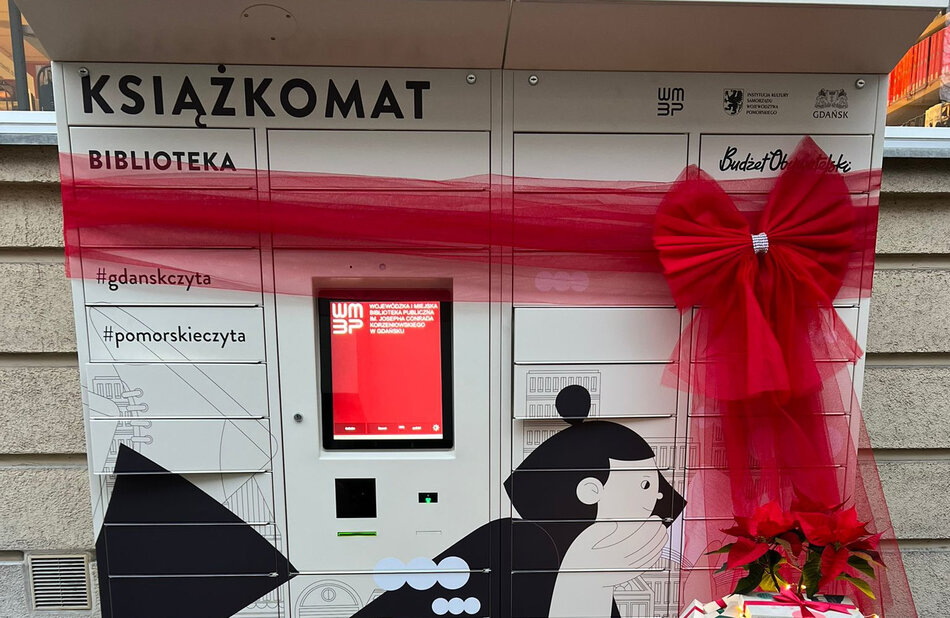 automat ze skrytkami na książki, przewiązany czerwoną wstęgą