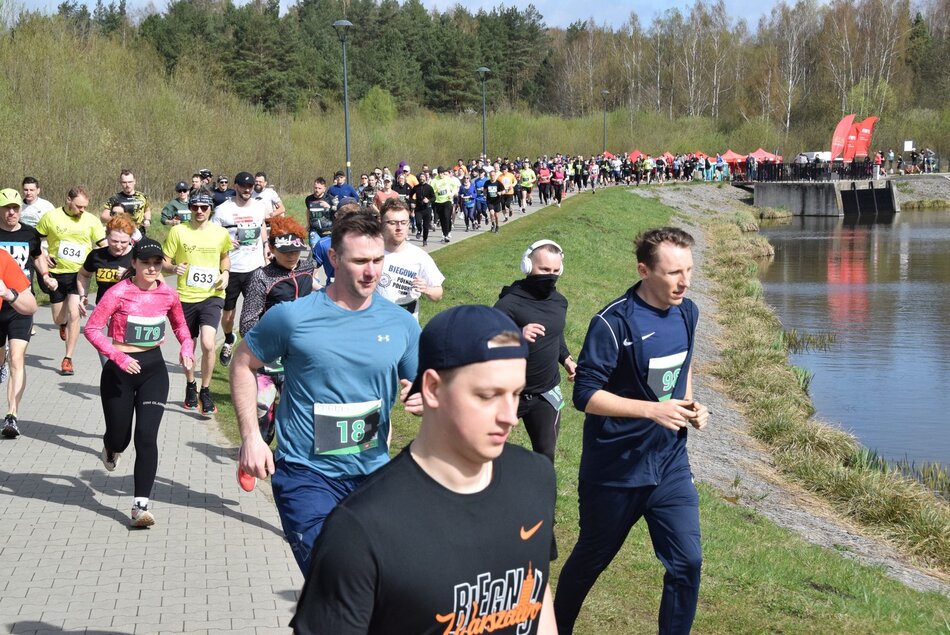 Kilkaset osób biegnie w ogonku, po prawej zbiornik wodny