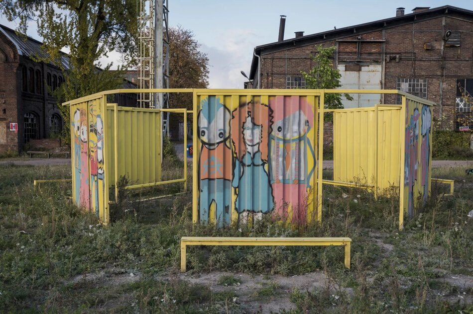 proste graffiti przedstawiające ludzi na żółtej metalowej konstrukcji