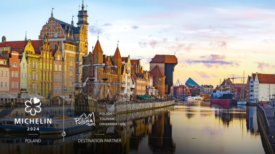 Na zdjęciu widać malowniczy widok na część Długiego Pobrzeża w Gdańsku, w Polsce. To znane miejsce jest często odwiedzane przez turystów ze względu na jego historyczną architekturę i piękny krajobraz nad rzeką Motławą. Widać kolorowe kamienice z charakterystycznymi szczytami, a także słynny Żuraw – historyczny dźwig portowy. Na pierwszym planie jest mały statek zakotwiczony przy nabrzeżu. Po prawej stronie obrazu można zauważyć dalszą część portu i nowoczesne budynki, które tworzą kontrast do starszej architektury. Niebo jest lekko zachmurzone, ale promienie słońca przebijają się przez chmury, co nadaje zdjęciu ciepłą atmosferę. Na obrazie dodane są logotypy - Michelin i Polska Organizacja Turystyczna, co sugeruje, że może to być materiał promocyjny.