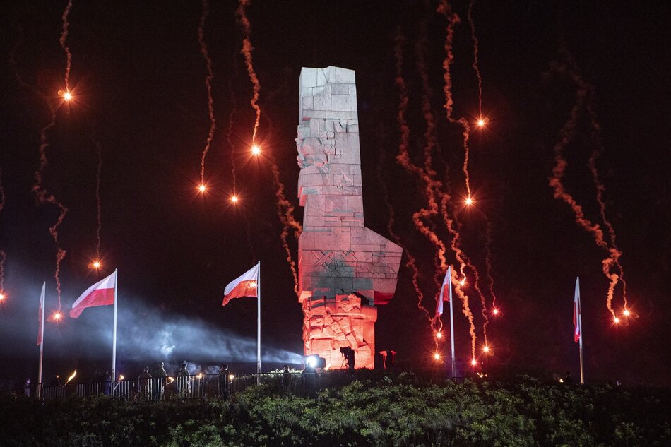 Pomnik na Westerplatte oświetlony czerwonymi racami. Jest ciemno, jeszcze przed wschodem słońca
