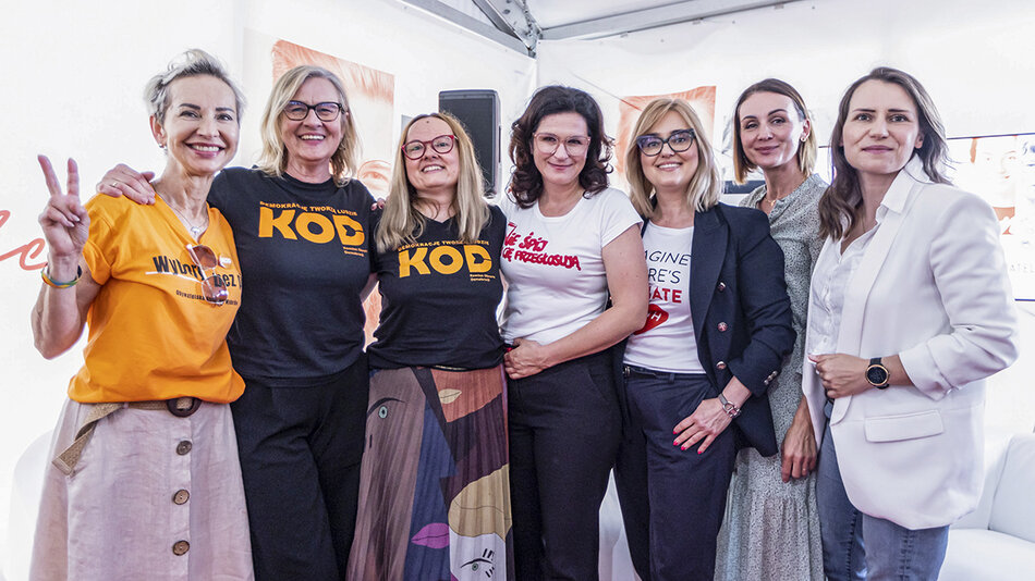Zdjęcie przedstawia siedem uśmiechniętych kobiet stojących obok siebie w grupie, co sugeruje, że zostało zrobione na zakończenie panelu dyskusyjnego lub spotkania. Wszystkie kobiety są elegancko ubrane i wyglądają na zadowolone oraz pełne energii.