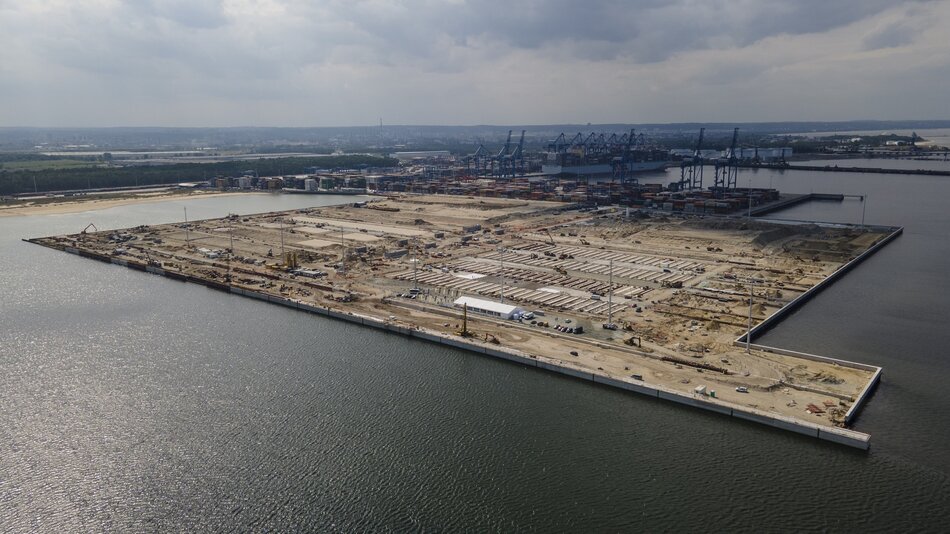 Na zdjęciu widać zaawansowane prace budowlane nad nowym nabrzeżem T3 w terminalu kontenerowym Baltic Hub. Widok z lotu ptaka pokazuje rozległy obszar budowy z licznymi maszynami oraz istniejące już struktury portowe w tle.