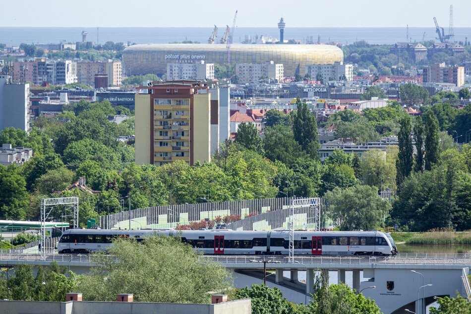 Widok miasta - oprócz budynków widać m.in. linię kolejową PKM i stadion Polsat Plus Arena Gdańska. W dalekim planie widać morze