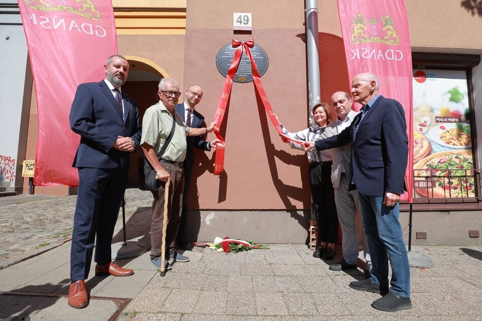 ludzie przed tablicą pamiątkową 