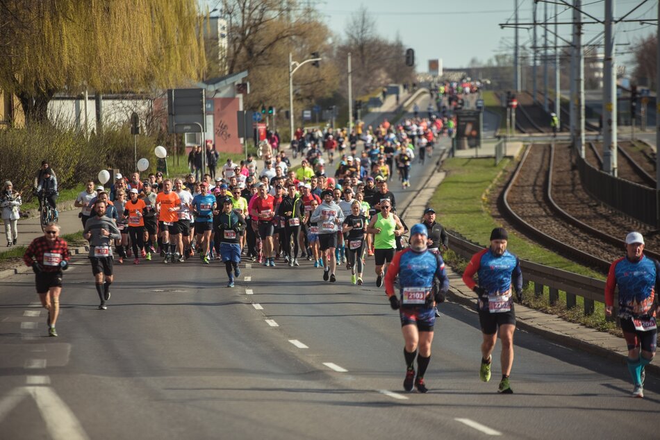 Tłum ludzi biegnie ulicą miasta.