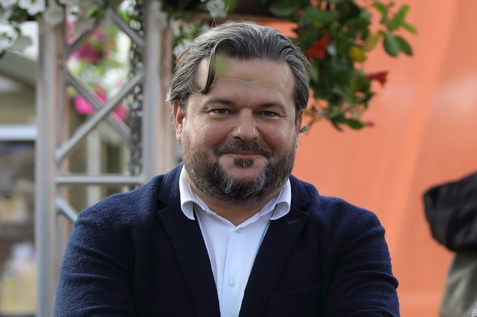 Uśmiechnięty mężczyzna z brodą w koszuli i garniturze