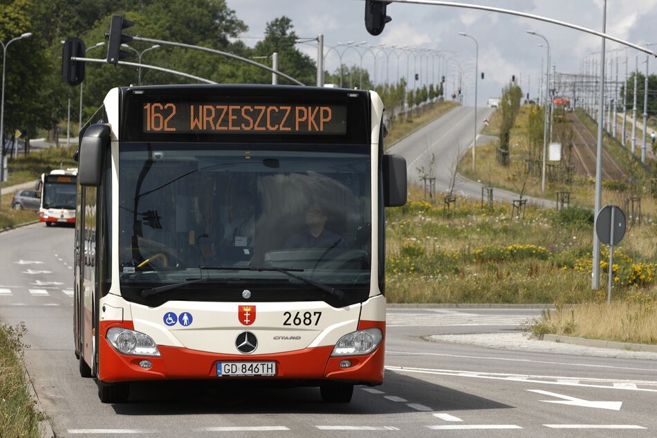 na zdjęciu autobus miejski, kremowo czerwony, jedzie ulicą