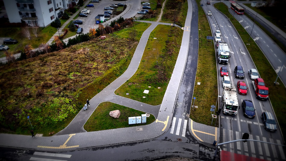 zdjęcie z drona, widać nowe chodniki, trawniki pomiędzy nimi, a także jezdnię z samochodami, w tle po lewej fragmenty bloków mieszkalnych