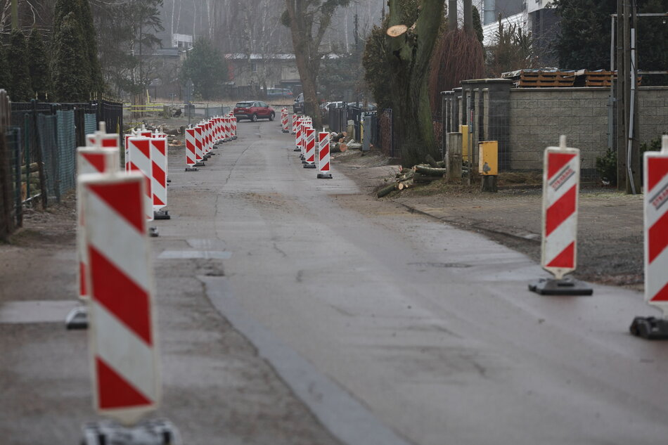 na zdjęciu jezdnia asfaltowa, po jej bokach ustawione biało - czerwone pionowe znaki drogowe, które zwężają jezdnię