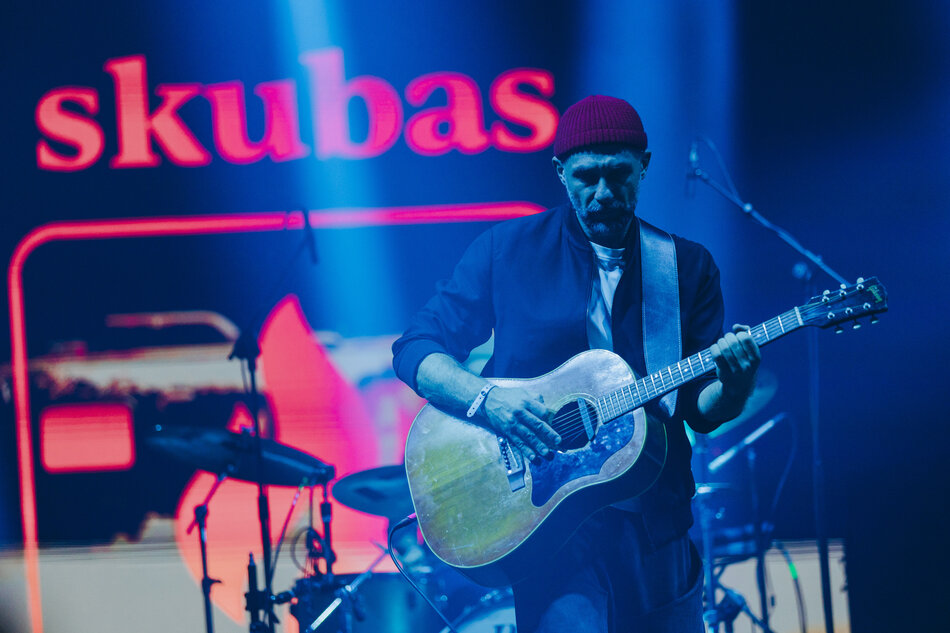 Mężczyzna z brodą i gitarą na scenie