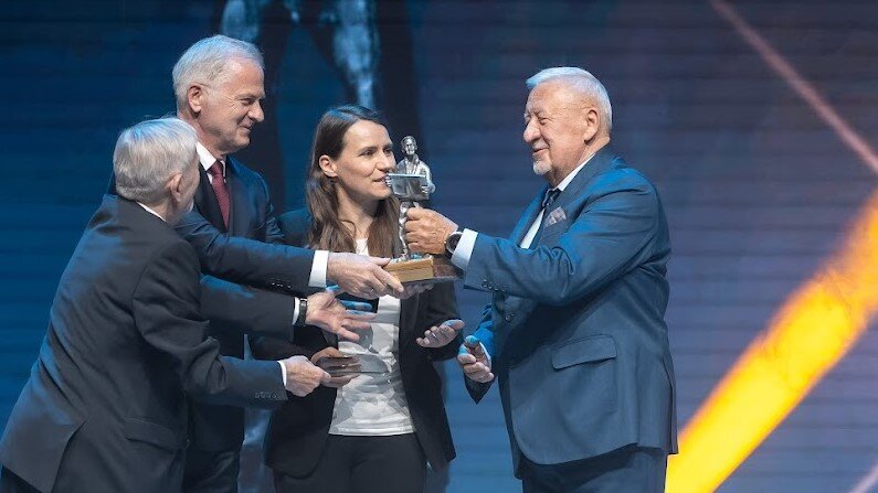 Grupa osób - mężczyzna odbierający statuetkę jest po prawej