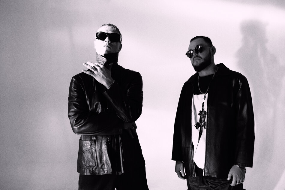 Na zdjęciu dwóch mężczyzn ubranych na czarno, w czarnych okularach przeciwsłonecznych.