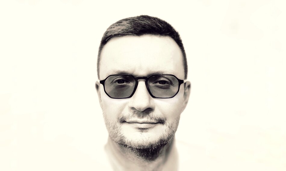 Zdjęcie przedstawia twarz mężczyzny w okularach.