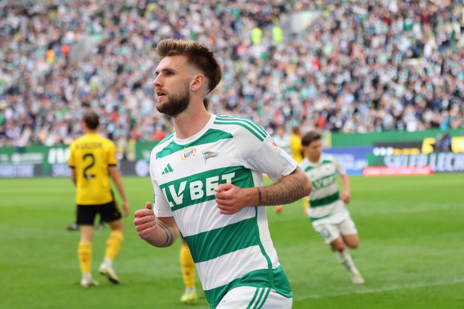 Piłkarz drużyny Lechia Gdańsk celebruje bramkę podczas meczu, na tle pełnych trybun stadionu. 