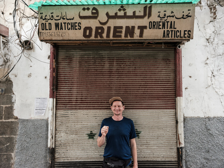 Na zdjęciu mężczyzna na tle szyldu z napisem orient.