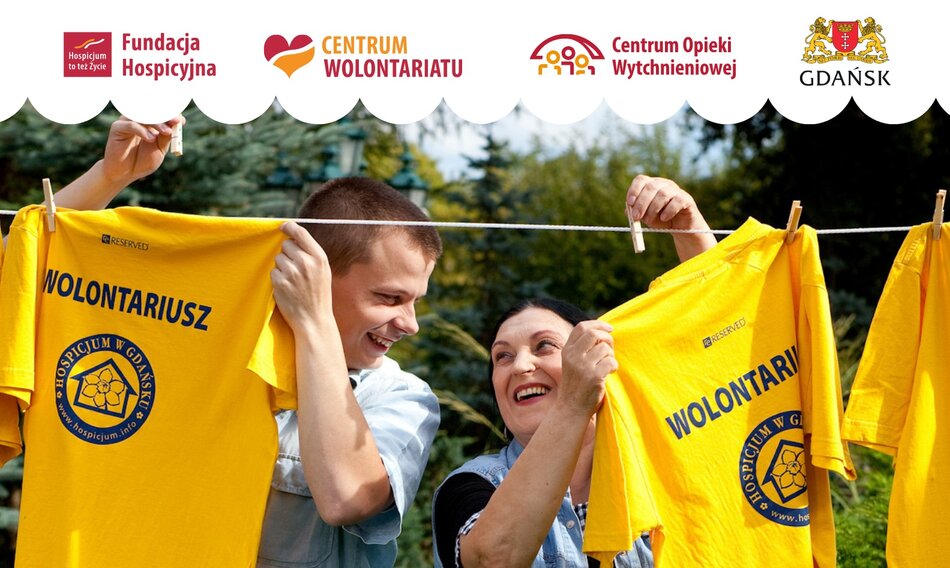 Na zdjęciu młody mężczyzna i kobieta z uśmiechem rozwieszają żółte koszulki z napisem „Wolontariusz” i logo Hospicjum w Gdańsku, co symbolizuje ich zaangażowanie w działalność społeczną. W górnej części widnieją logotypy Fundacji Hospicyjnej, Centrum Wolontariatu, Centrum Opieki Wytchnieniowej oraz miasta Gdańsk, wskazując na wspólne działania promujące wolontariat i opiekę hospicyjną. 