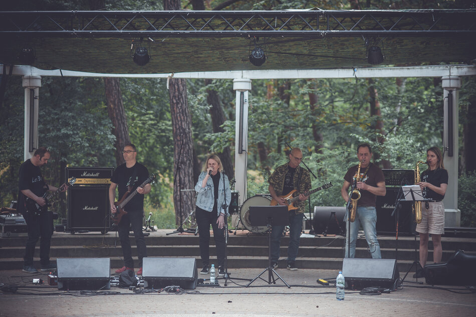 sześcioro muzyków na scenie w parku podczas koncertu