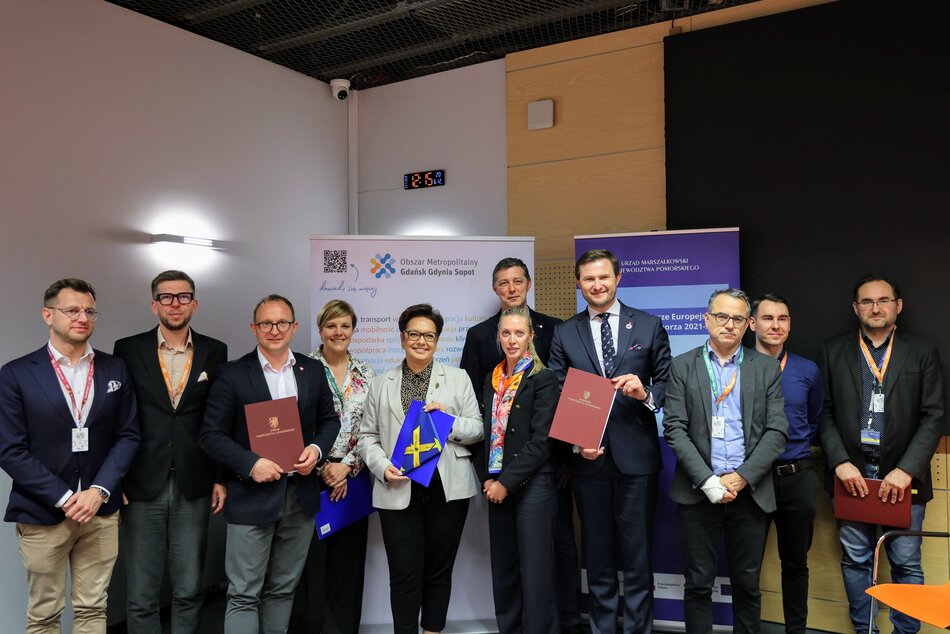 Grupa osób pozuje do fotografii z podpisanymi umowami.