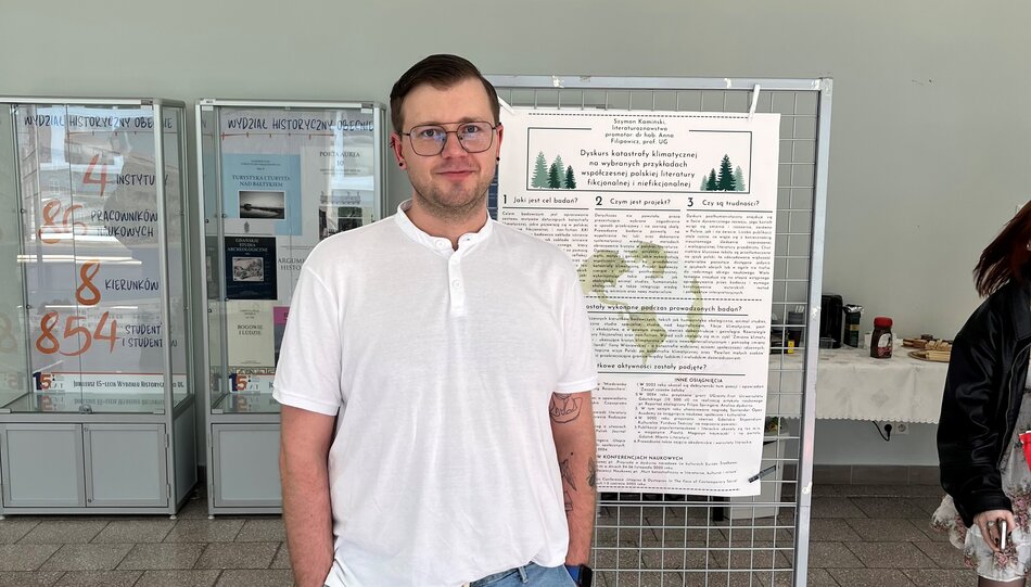 Na zdjęciu mężczyzna w okularach, w białej koszulce.