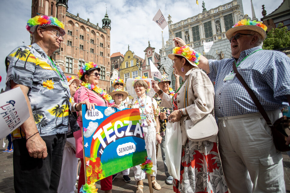 Grupa wesołych i przebranych kolorowo seniorów podczas parady w mieście.