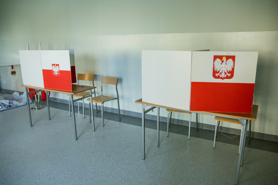 Komisja wyborcza, stoły z białoczerwonymi parawanami do głosowania.