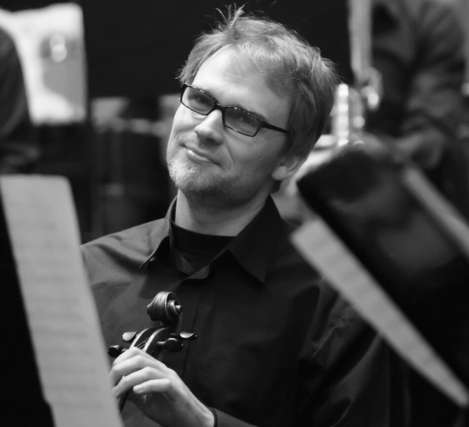 Na zdjęciu mężczyzna trzymający instrument smyczkowy.