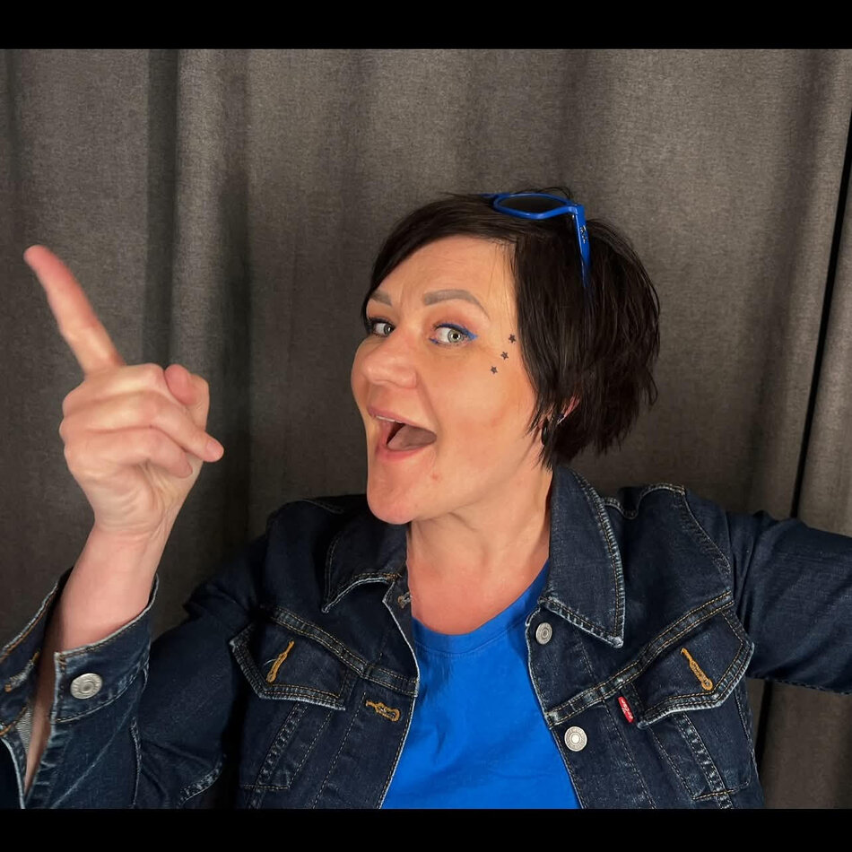 Na zdjęciu kobieta o krótkich włosach, wystawiająca palec wskazujący w prawo.