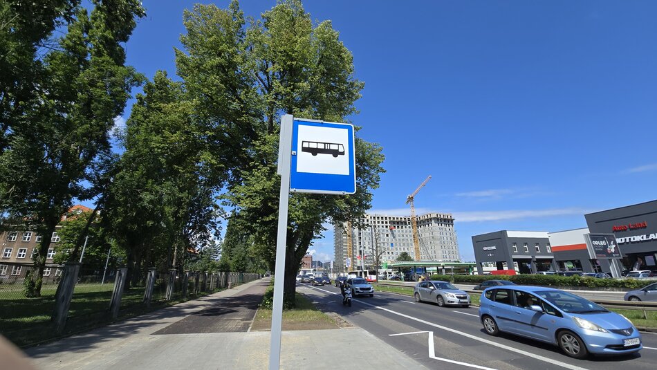 na zdjęciu znak drogowy na słupku przedstawia autobus na niebosko białym tle, informuje o tym, że jest to przystanek autobusowy
