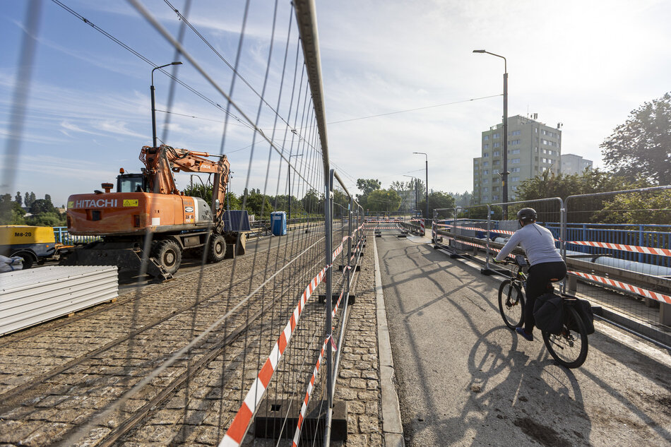 na zdjęciu most po którym jedzie rowerzysta, po lewej widać metalowe siatkowe ogrodzenie