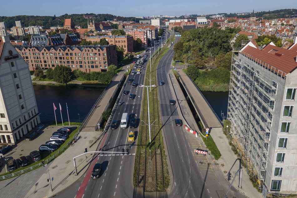 zdjęcie z drona, widać ulicę, po której jedzie kilka samochodów, po obu stronach stoją wysokie kamienice