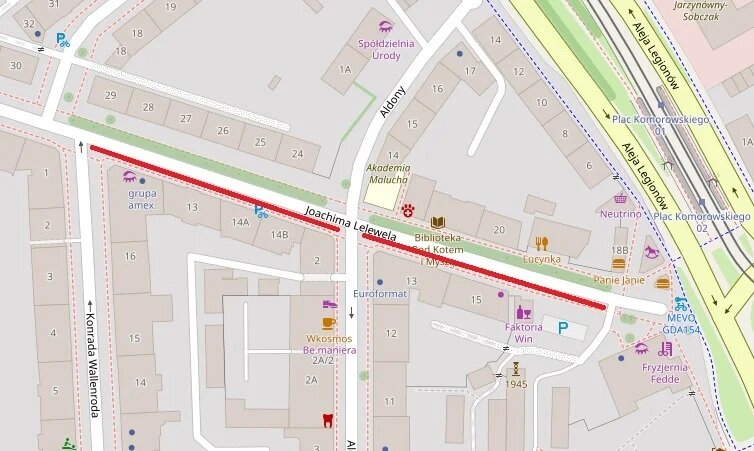 Mapa przedstawia fragment ulic w mieście. Centralnie zaznaczona jest ulica Joachima Lelewela biegnąca poziomo, oznaczona czerwoną linią. Po jej północnej stronie widoczne są budynki oznaczone numerami od 14 do 29, a także miejsca takie jak Akademia Malucha, Biblioteka z Kotem i My, Eugenika, czy Spółdzielnia Urody. Na południe od ulicy Lelewela znajdują się budynki oznaczone m.in. numerami 14A, 12, 11, 2A oraz punkty usługowe i handlowe, jak Euroformat, Faktoria Win, Wkosmos Bemaniara, czy grupa amex.