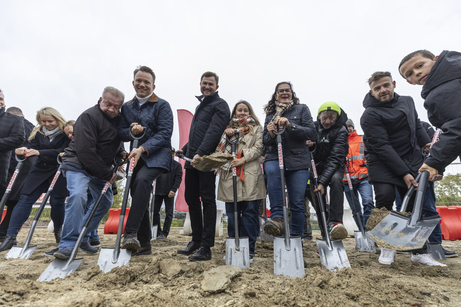 na zdjęciu grupa osób w średnim wieku, w jesiennych ciepłych ubraniach, pozują do zdjęcia z łopatami