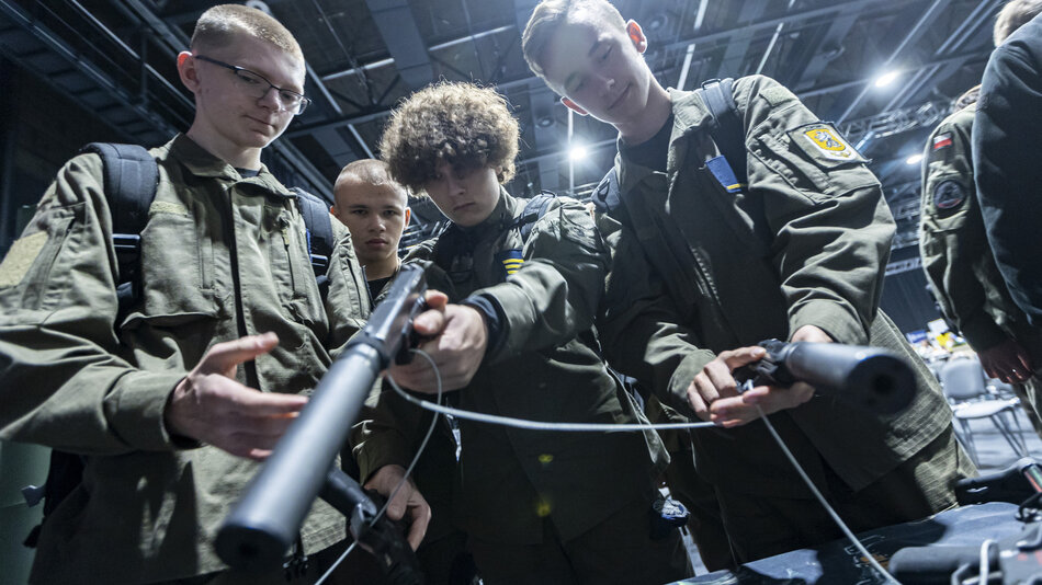 grupa chłopców ubranych w mundury bawi się bronią we wnętrzu dużej targowej hali