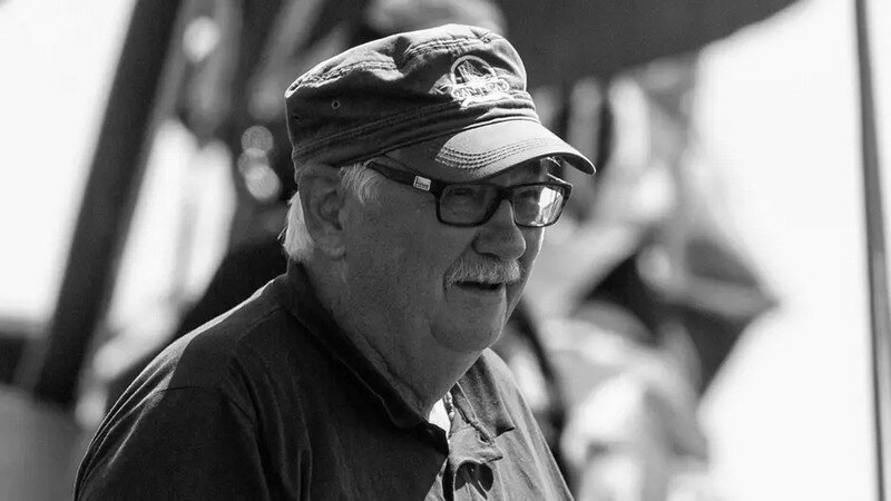 Czarno-białe zdjęcie. Starszy mężczyzna w czapce z daszkiem i okularach